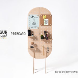 May include: A freestanding pegboard with shelves and a corkboard. The pegboard is made of light wood and has a rounded top. It has a variety of items on it, including pens, pencils, a plant, and a small glass jar. The pegboard is labelled "PEGBOARD" and "PEGUP Legged". The text "For Office | Home | Makers" is at the bottom of the image.