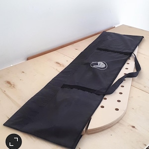 May include: A black canvas bag with a zipper and a handle. The bag is lying on a light wood surface. The bag has a white logo that says "Rock Solid" on it.