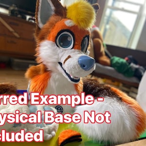 May include: A furry orange, white and brown fox head with a yellow pom-pom on top. The head is sitting on a table with a green surface. The text "Furred Example - Physical Base Not Included" is visible in the image.