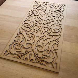 May include: A decorative wooden panel featuring an intricate, laser-cut design of swirling floral patterns. The panel is made from light brown wood and has a natural finish.