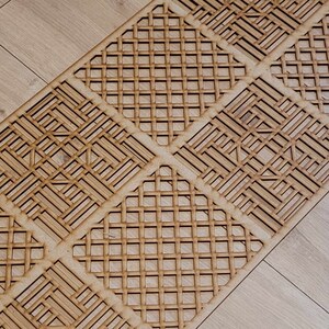 May include: A wooden decorative runner with a geometric pattern. The runner is made of light brown wood and has a repeating pattern of squares and diamonds.