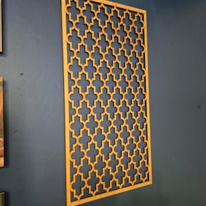 May include: A decorative wooden wall panel with a geometric pattern. The panel is made of light brown wood and has a repeating pattern of interlocking squares and diamonds.