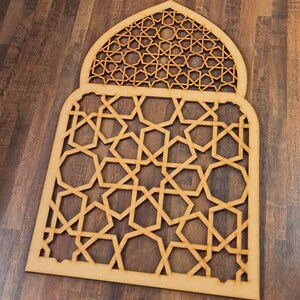 May include: A wooden cutout of an Islamic archway with intricate geometric patterns. The design features a repeating star and diamond pattern.