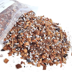 Peut inclure: Un sac en plastique transparent avec un mélange de terre brun, blanc et noir qui s'en échappe. Le sac est étiqueté "Aroid Mix".