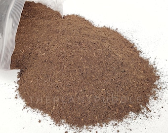 May include: A close-up of a brown, loose, fibrous material, likely a type of soil or compost, spilling out of a clear plastic bag onto a white surface.