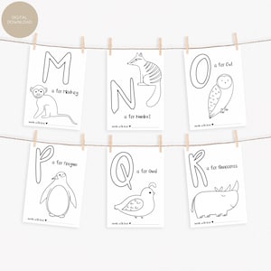 May include: Six black and white alphabet flashcards with animal illustrations, including a monkey, owl, penguin, and rhinoceros. Each card features a letter and the animal's name. The cards are hanging from a string with wooden clothespins.