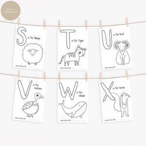 May include: A set of six black and white alphabet art prints, each featuring a letter and an animal illustration. The prints are suspended from a string with wooden clothespins. The letters are S, T, U, V, W, and X, with corresponding animals like a sheep, tiger, and whale.