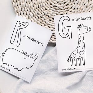 May include: Two white cards with black line drawings of animals and letters. One card says "K is for Rhinoceros" with a rhino illustration. The other says "G is for Giraffe" with a giraffe illustration. Both cards say "made with love".