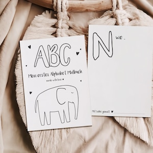 Może przedstawiać: Dwie białe karty z czarnymi konturami i tekstem. Jedna karta ma litery "ABC" i ilustrację słonia. Tekst brzmi "Mom erstes Alphabet Malbuch made with love." Druga karta ma literę "N" oraz tekst "wie." i "Mit Liebe gemalt!"
