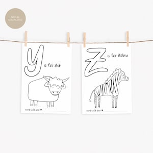 May include: Two black and white prints hanging from a string with wooden clips. One print features the letter "Y" and a yak illustration with the text "Y is for yak". The other print shows "Z is for Zebra".