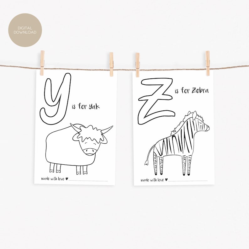 May include: Two black and white prints hanging from a string with wooden clips. One print features the letter "Y" and a yak illustration with the text "Y is for yak". The other print shows "Z is for Zebra".