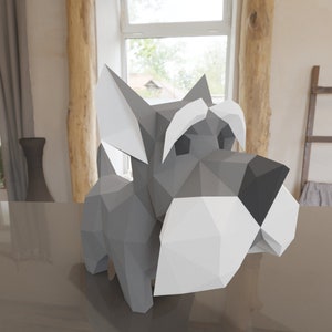 Op de afbeelding: Een grijs en wit papieren model van een miniatuur schnauzer. De hond staat op een grijs oppervlak.