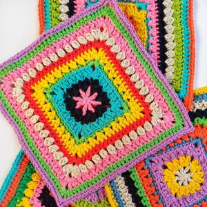 May include: Four colorful crocheted squares with different patterns. The squares are made with a variety of colors, including pink, yellow, green, blue, orange, and black.