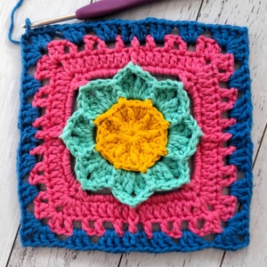 May include: A crocheted square with a multi-colored flower design. The flower is made of yellow, teal, and turquoise yarn. The square is bordered with blue and pink yarn.