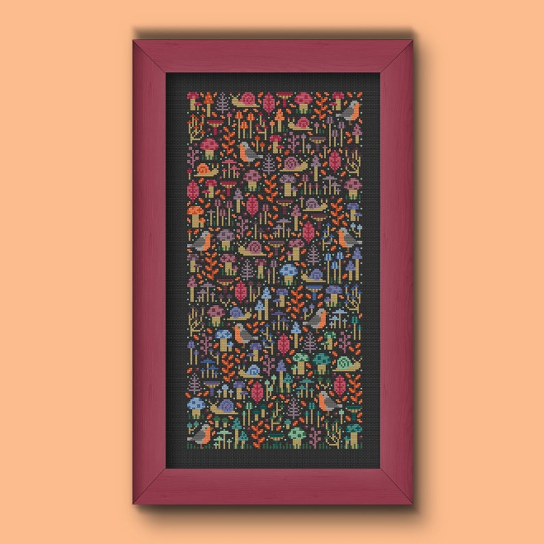 Cross stitch sample pattern. Mushrooms, snails and birds embroidered on black Aida fabric. Fall colors palette (dusty red, autumn orange, beige, warm purple, sky blue and mint green). Framed on a garnet frame and put on a pale orange background.