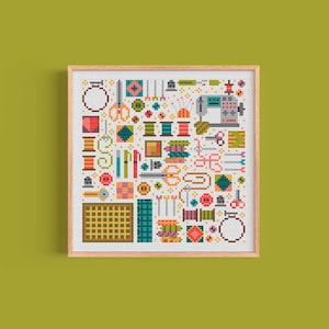 Può includere: Un motivo a punto croce colorato che presenta una varietà di articoli per cucire e artigianato, tra cui bobine di filo, bottoni, forbici, aghi e una macchina da cucire. Il motivo è su uno sfondo bianco e incorniciato in una cornice di legno chiaro.