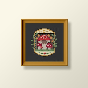 Fungi inspired framed cross stitch chart. The cross stitch design consists on a some mushrooms surrounded by a frame decorated with a moon, stars and leaves. The art style is cottagecore, witchy and whimsical. The colors of the design are red, yellow, orange and green. This cross stitch design is modern, unique and original. Stitched on black Aida fabric. Available to download as a cross PDF stitch pattern.
