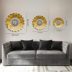 May include: Three gold-colored, flower-shaped wall decorations with Arabic calligraphy. The largest is 26 inches in diameter, the middle one is 19 inches, and the smallest is 13 inches. Each has a blue and gold center. They are displayed above a gray sofa.