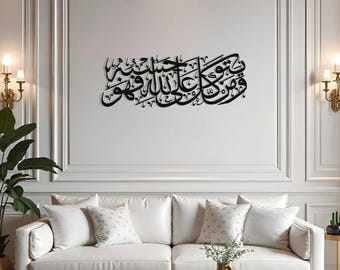 May include: Black metal wall art featuring Arabic calligraphy script. The artwork is mounted on a white wall above a white sofa with decorative pillows. The room is decorated with gold accents and sconces.