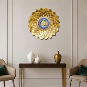 May include: A gold-colored, circular wall art piece with a floral design, featuring Arabic calligraphy in the center. The artwork is mounted on a white wall, with a dark brown table and decorative vases below. Two chairs with green pillows are on either side.