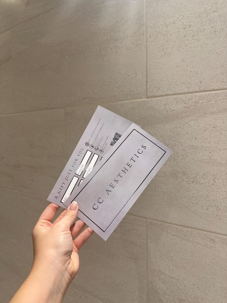 May include: A gift certificate from CC Aesthetics, held in a hand. The certificate is light gray with the text "A GIFT JUST FOR YOU" and "CC AESTHETICS". It has spaces for "TO", "VALUE", and "EXPIRY", along with a QR code.