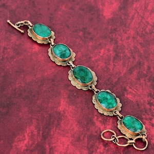 May include: A gold bracelet with five oval-shaped green gemstones. The bracelet has a clasp closure.