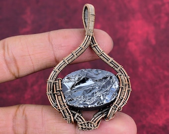 May include: A wire-wrapped pendant featuring a central oval-shaped, metallic dark gray stone encased in intricate copper wire coils. The copper wire forms a teardrop-shaped frame with a decorative bail at the top, showcasing detailed metalwork.