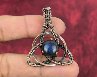 May include: A copper wire wrapped pendant with a blue labradorite gemstone in the center. The pendant is in the shape of a Celtic knot.