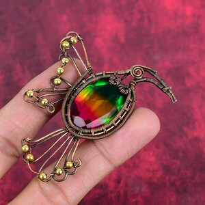 Peut inclure: Un pendentif en fil de cuivre en forme de colibri avec une pierre précieuse irisée multicolore. Le pendentif présente un design de fil détaillé et des perles dorées.