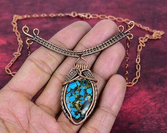 May include: A copper wire-wrapped necklace featuring a central oval pendant with a mosaic of bright blue and dark metallic stone fragments. The pendant is suspended from a curved, woven copper wire collar attached to a matching copper chain link necklace.
