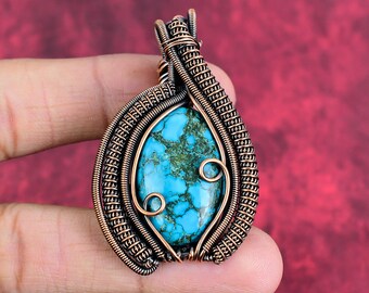May include: A pendant featuring a central marquise-shaped turquoise stone with dark matrix veining, encased in an intricate frame of coiled copper wire. The wirework forms a decorative spiral pattern on the front and a bail at the top.