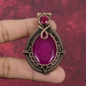 May include: A copper wire wrapped pendant featuring a large oval shaped pink gemstone with a smaller pink gemstone at the top.