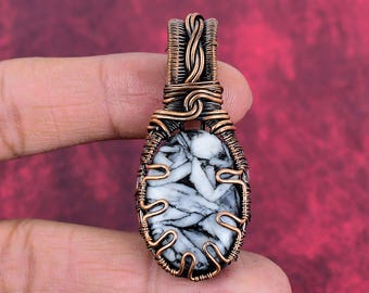 May include: An oval-shaped pendant featuring a white and black patterned stone encased in intricate, hand-woven copper wire. The wirework forms a decorative frame around the stone and extends upward into a braided bail for hanging the piece.