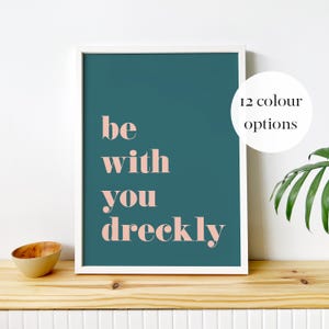 May include: A white framed print with a teal background and the text "be with you dreckly" in pink lettering.