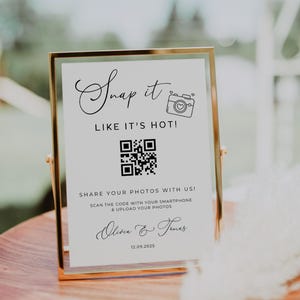 Pode incluir: Um letreiro retangular branco com moldura dourada, com o texto "Snap it LIKE IT'S HOT!" e um código QR. O letreiro também inclui o texto "COMPARTILHE SUAS FOTOS CONOSCO!" e os nomes "Olivia & Temas" com a data 12.09.2025.