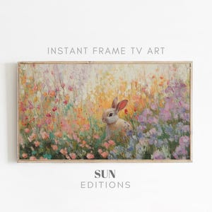 Può includere: Stampa artistica digitale incorniciata raffigurante un coniglio in un campo di fiori colorati. L'opera d'arte ha uno stile morbido e impressionistico con colori pastello. Il testo in alto recita "INSTANT FRAME TV ART" e in basso "SUN EDITIONS".