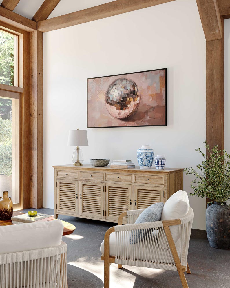 May include: A light wood cabinet with four doors and three drawers. The cabinet has a white top and is decorated with a silver disco ball painting. A white wicker chair with a blue cushion sits in front of the cabinet.