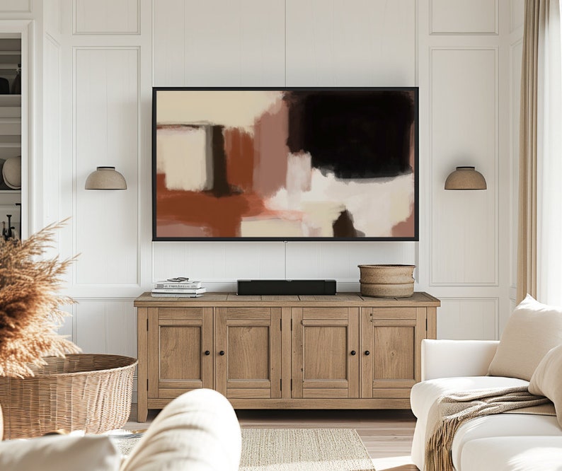 May include: A living room interior with a wooden cabinet, a white couch, and a framed abstract painting above the cabinet. The painting features shades of brown, beige, and black.