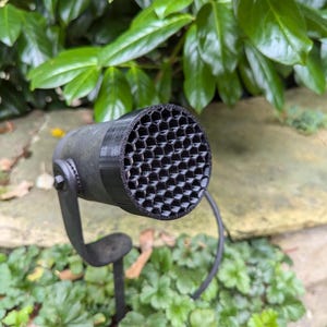 Könnte beinhalten: Ein schwarzes Mikrofon mit einem sechseckigen Gitter an der Vorderseite. Das Mikrofon ist auf einem schwarzen Ständer montiert.