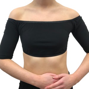 May include: Black off-the-shoulder crop top with three-quarter sleeves. The top is made of a soft, stretchy fabric and features a straight neckline and a cropped hemline. The sleeves end just below the elbow. Suitable for dance or other activities.