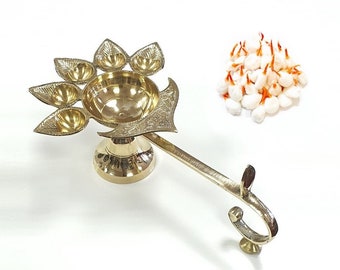 Peut inclure: Un diya en métal doré avec sept mèches, une poignée décorative et une base. Le diya est conçu pour contenir de l'huile et des mèches pour les cérémonies indiennes traditionnelles.