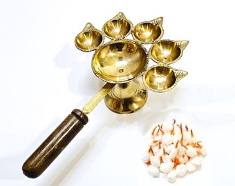 Peut inclure: Un diya en laiton avec une poignée en bois et cinq mèches. Le diya présente un design décoratif et est parfait pour les cérémonies religieuses ou la décoration de la maison.