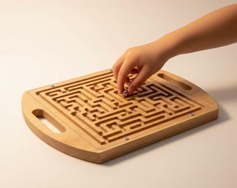 Puede incluir: Un juego de laberinto de madera con una bola de metal. El laberinto está tallado en una tabla de madera rectangular con esquinas redondeadas y asas. Se muestra una mano guiando la bola a través del laberinto.