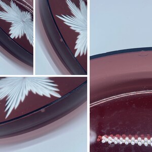 Pu&ograve; includere: Un set di tre piatti vintage in vetro trasparente a forma di cuore con una tinta bordeaux e un motivo a stella bianca. I piatti sono leggermente curvi e hanno un bordo rialzato.