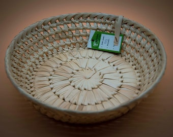 May include: A round, woven basket made of natural materials. The basket is light brown in color and has a woven pattern. A small green tag with the text "Ecotope" and "013" is attached to the basket.