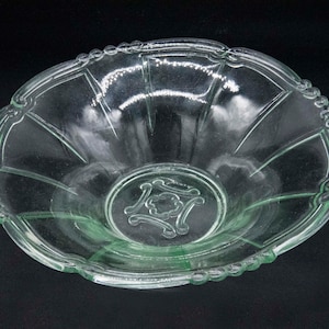Peut inclure: Un bol en verre transparent avec un bord festonné et un motif décoratif au centre. Le bol est de couleur vert pâle.