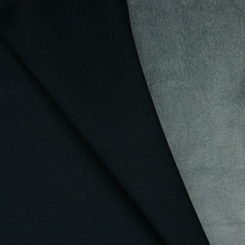 May include: A piece of fabric featuring two distinct sections. The left side is a solid, deep black color with a smooth, matte texture. The right side is a contrasting heathered gray fabric with a visible, slightly textured weave pattern.