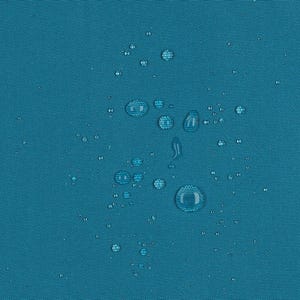 May include: A solid teal fabric surface featuring a tight, woven texture. Numerous clear water droplets of varying sizes are scattered across the material, demonstrating a water-repellent quality with beads resting on the surface.