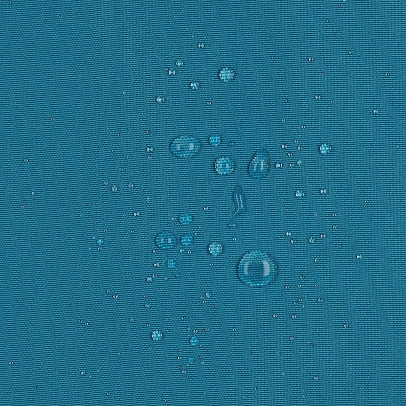 May include: A solid teal fabric surface featuring a tight, woven texture. Numerous clear water droplets of varying sizes are scattered across the material, demonstrating a water-repellent quality with beads resting on the surface.