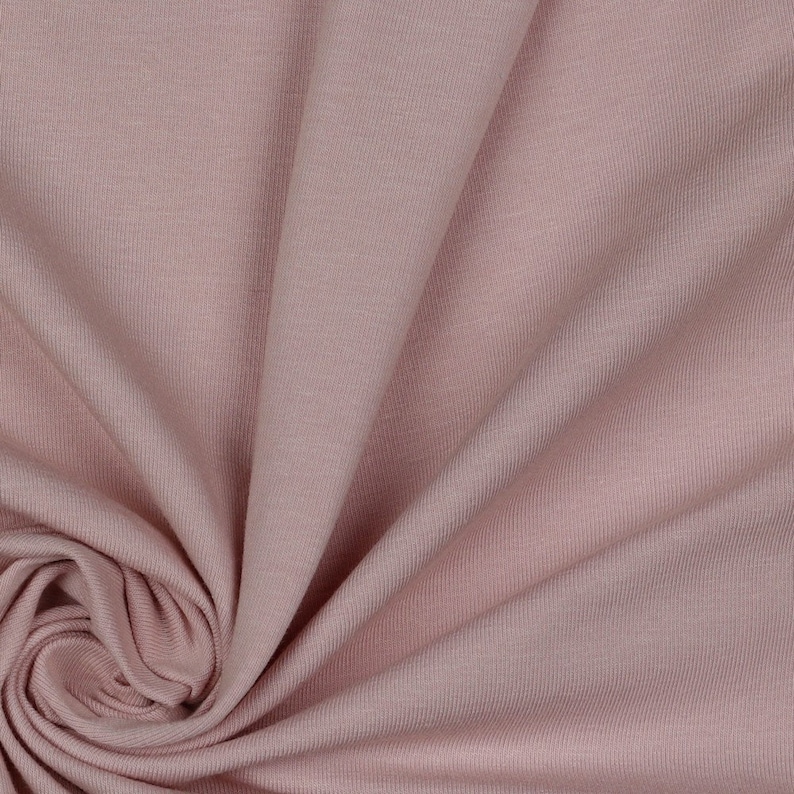May include: Close-up of a soft, pink ribbed fabric. The fabric is smooth and has a subtle sheen.